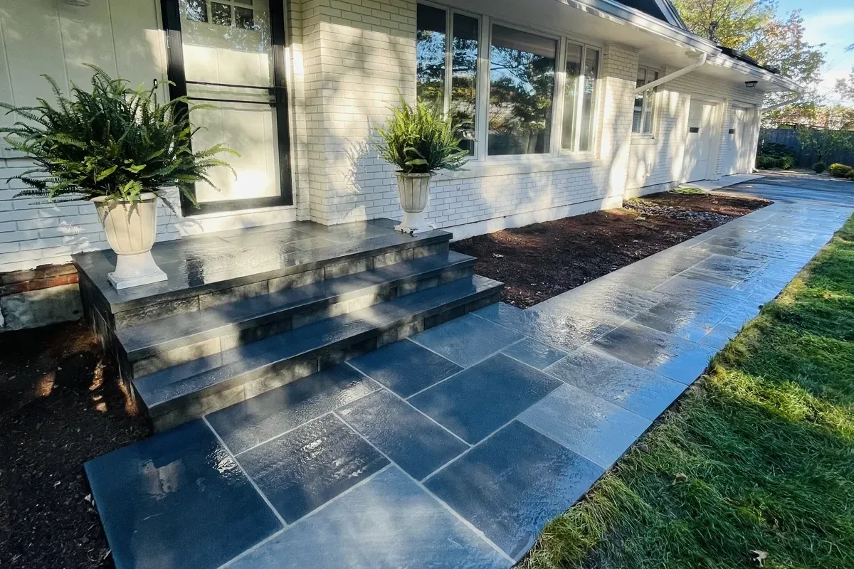 New blue-gray stone front steps and stone slab walkway along a white brick ranch house
